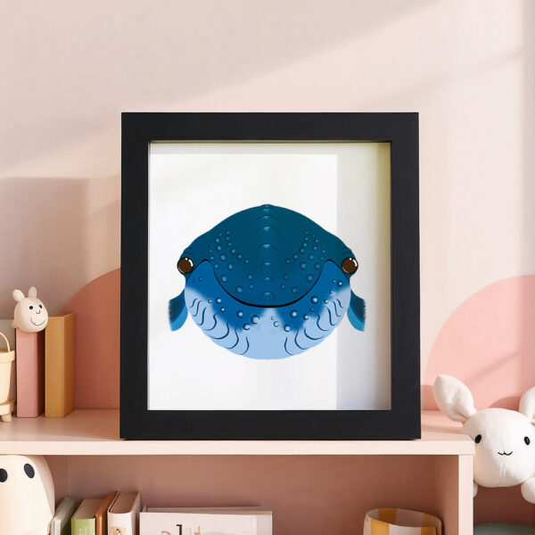 Illustration d’une baleine souriante dans un cadre noir, posé dans une chambre d’enfant.
