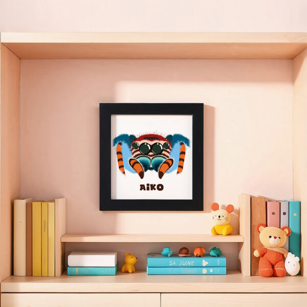 Illustration d’une araignée souriante et le prénom Aiko en dessous dans un cadre noir, posé dans une chambre d’enfant.